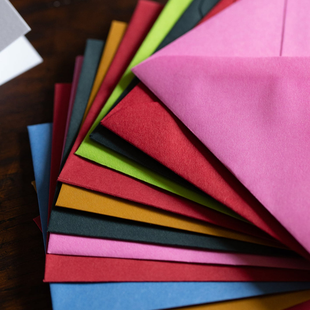 Set of colorful envelopes arranged in a fan on a wooden surface