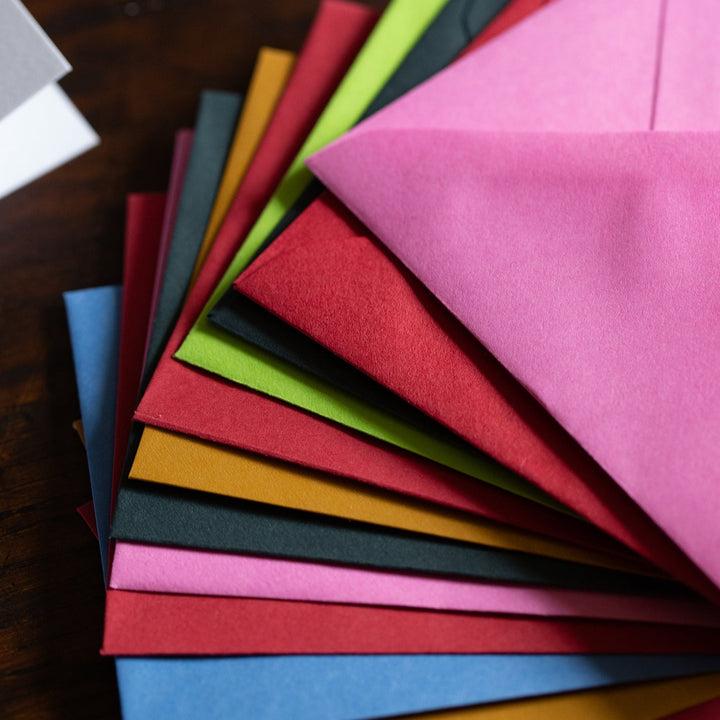 Set of colorful envelopes arranged in a fan on a wooden surface