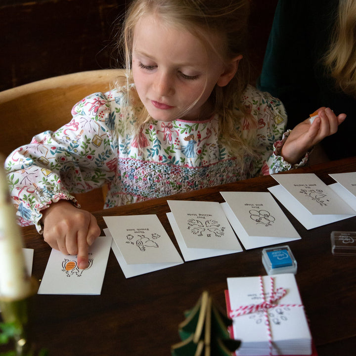 Young girl sitting at a table with greeting cards and a small gift box.