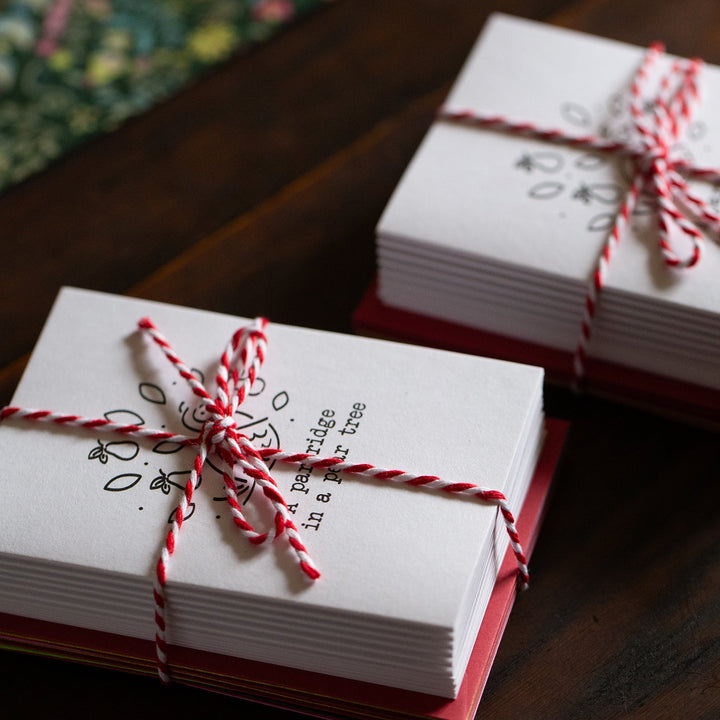 Stacks of white cards tied with red string on a wooden surface