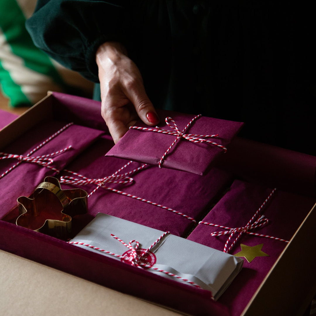 Hand holding a purple gift box with string ties, close-up shot.