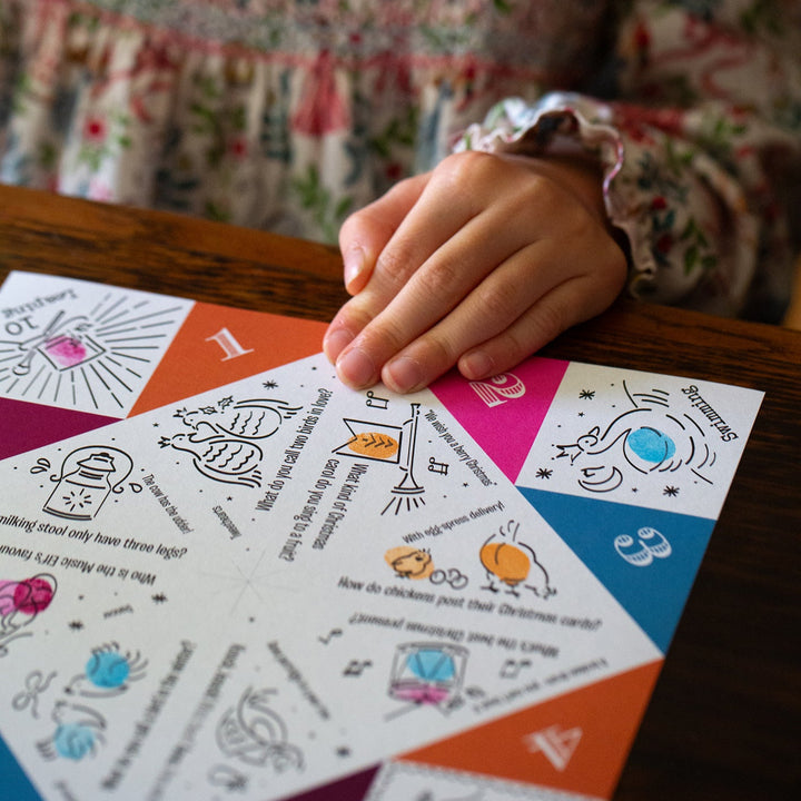 Child's hand on a colourful card with illustrations