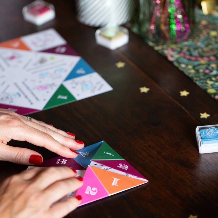 Colourful joke teller pieces on a wooden table with a hand interacting with them.