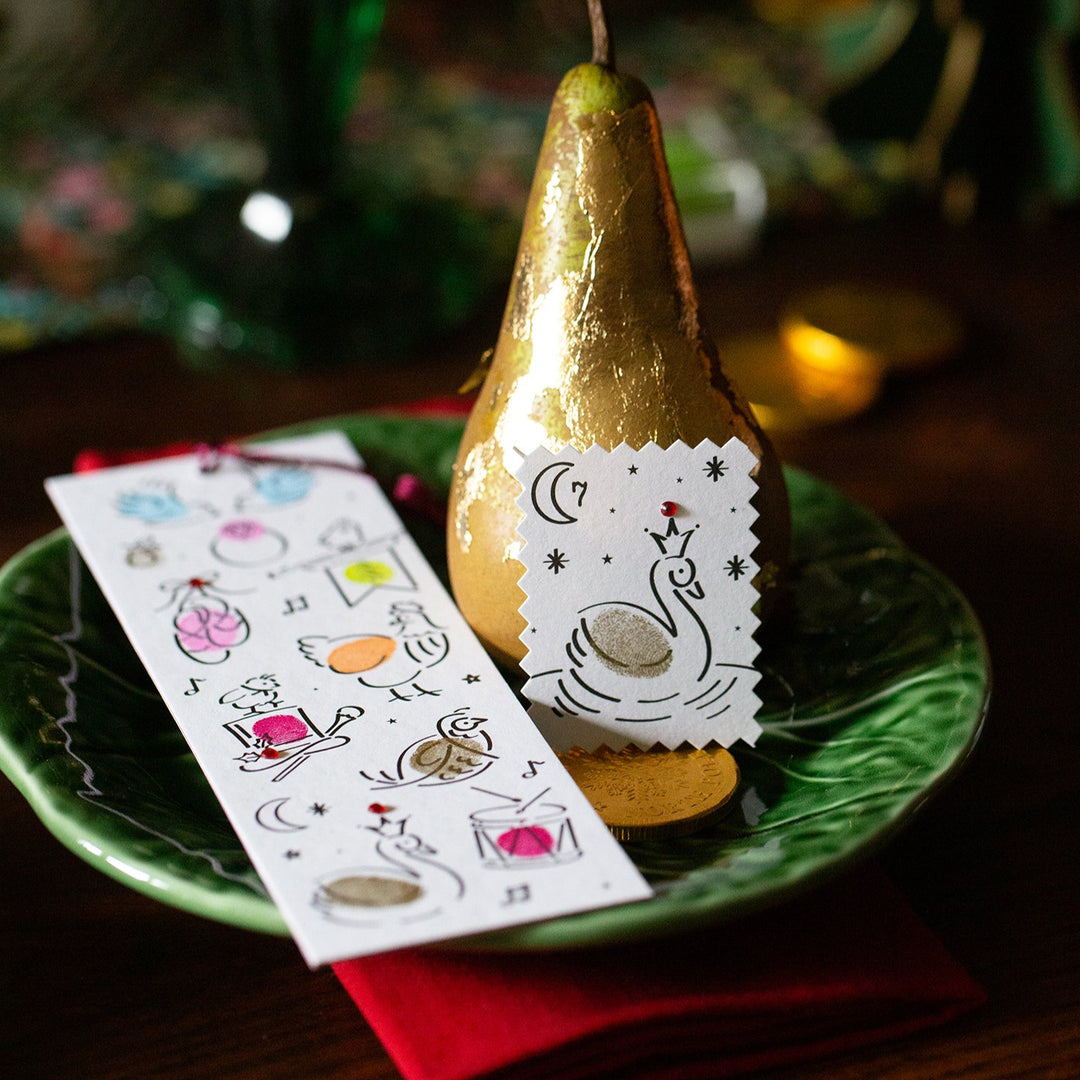 Gold pear on a green plate with a Christmas Bookmark and place card on a wooden surface