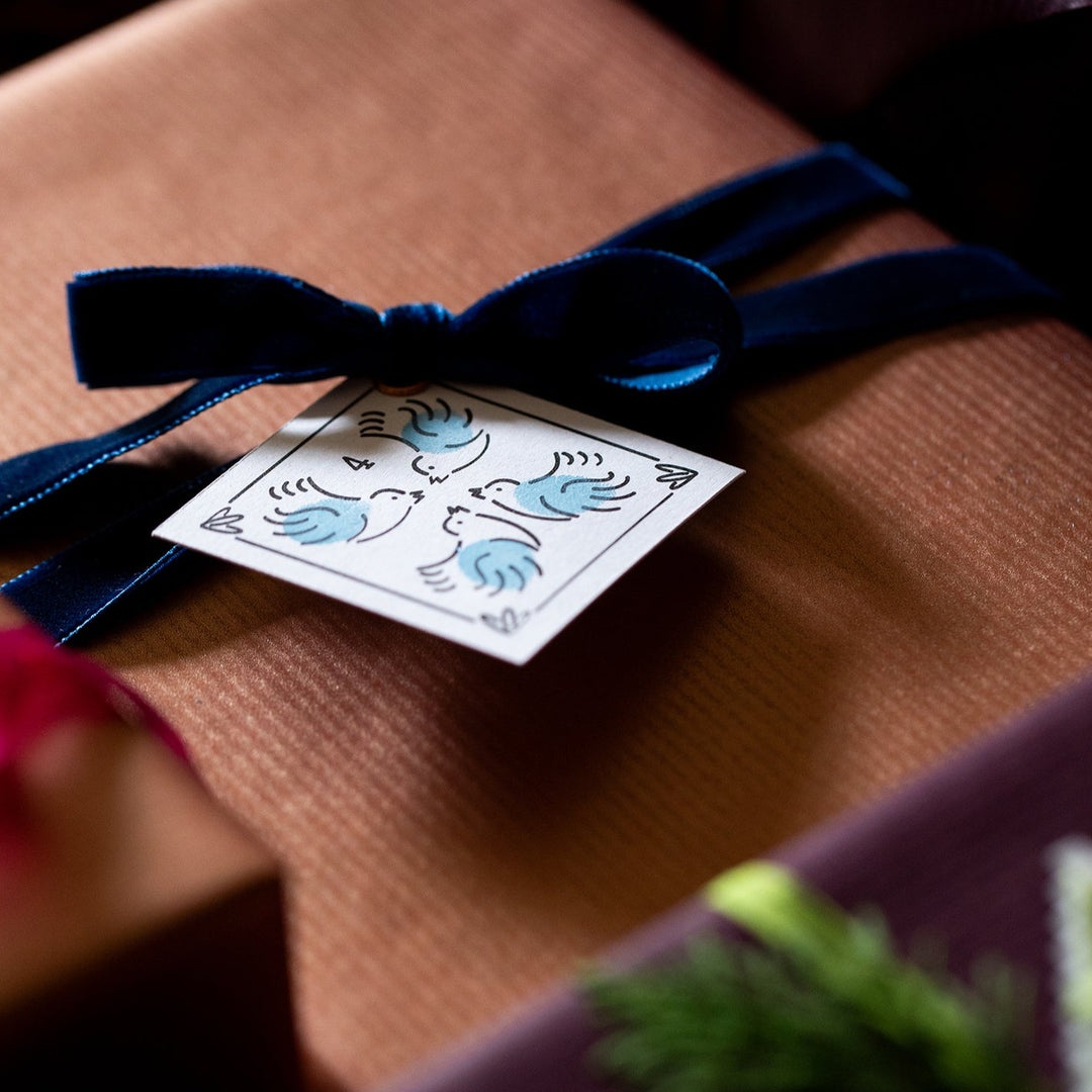 Gift wrapped in brown paper with a blue ribbon and 12 Days of Christmas Gift label.